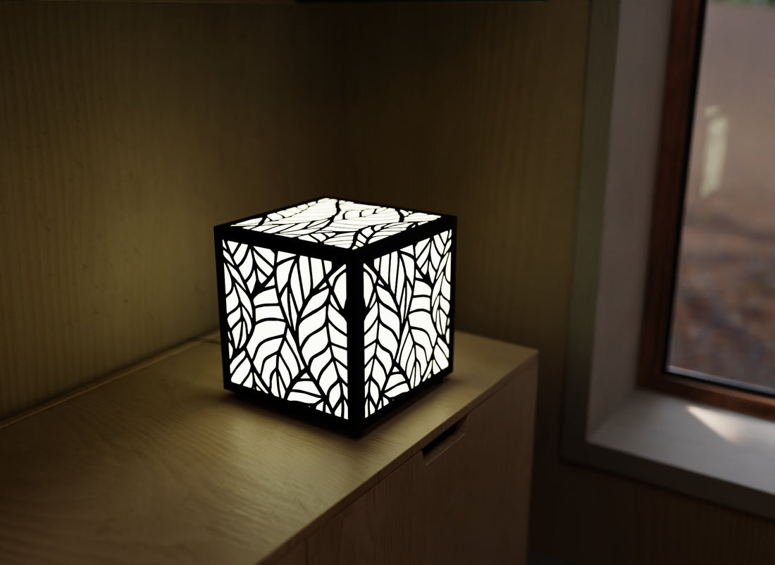 300mm metal cube lamp featuring a leafy cut-out pattern, white plexiglass panels, and a textured black finish.
