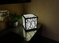 300mm metal cube lamp featuring a leafy cut-out pattern, white plexiglass panels, and a textured black finish.
