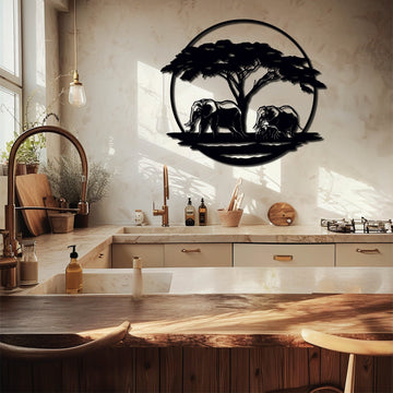 Metal wall art depicting two elephants standing under an acacia tree, enclosed within a circular frame, displayed in a modern kitchen with warm natural light and rustic decor