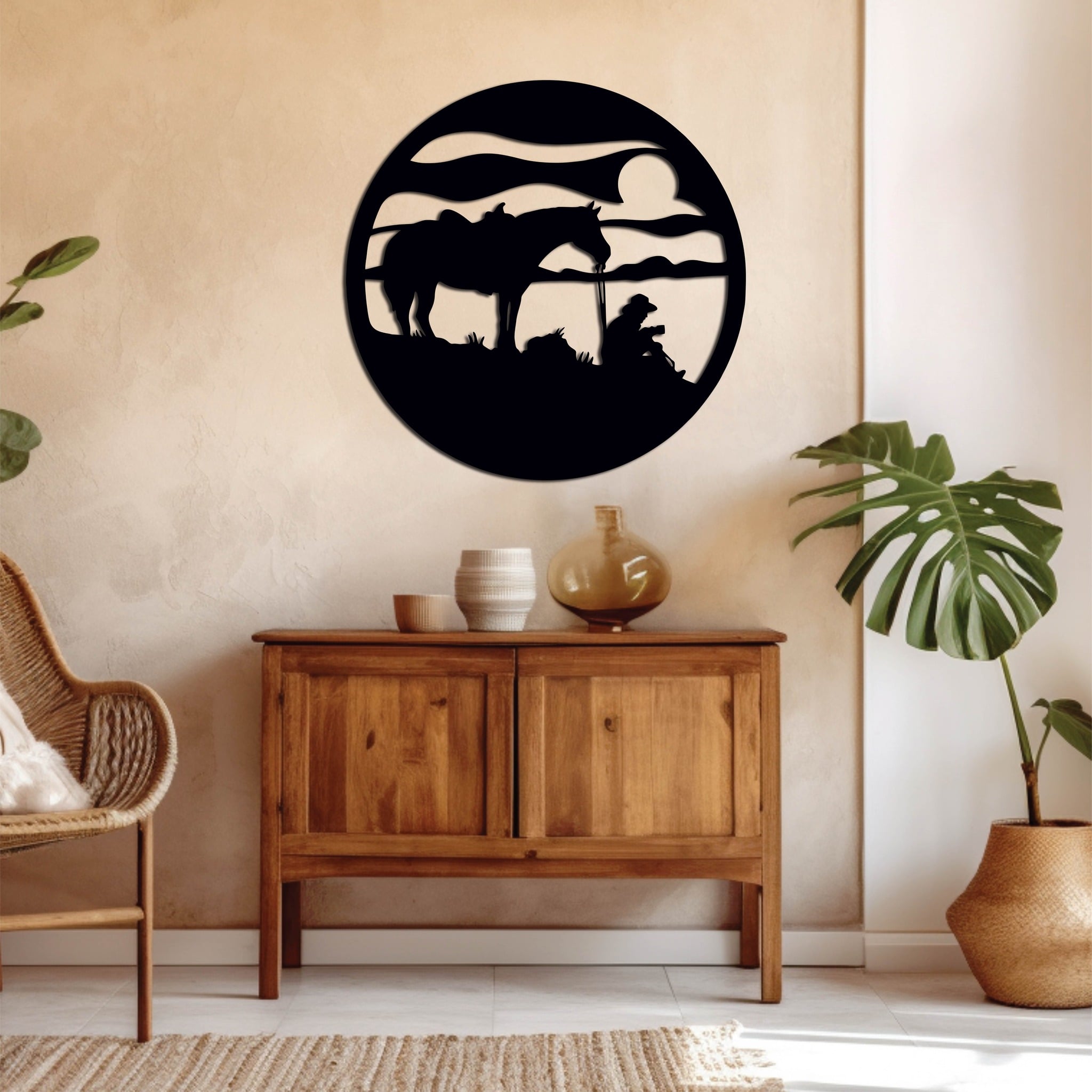 Circular metal artwork of a cowboy sitting in a field with his horse at dusk, evoking a serene western scene in a warm-toned interior.