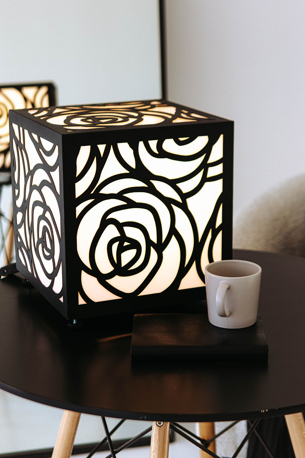 Decorative lamp with floral pattern on a table next to a mug