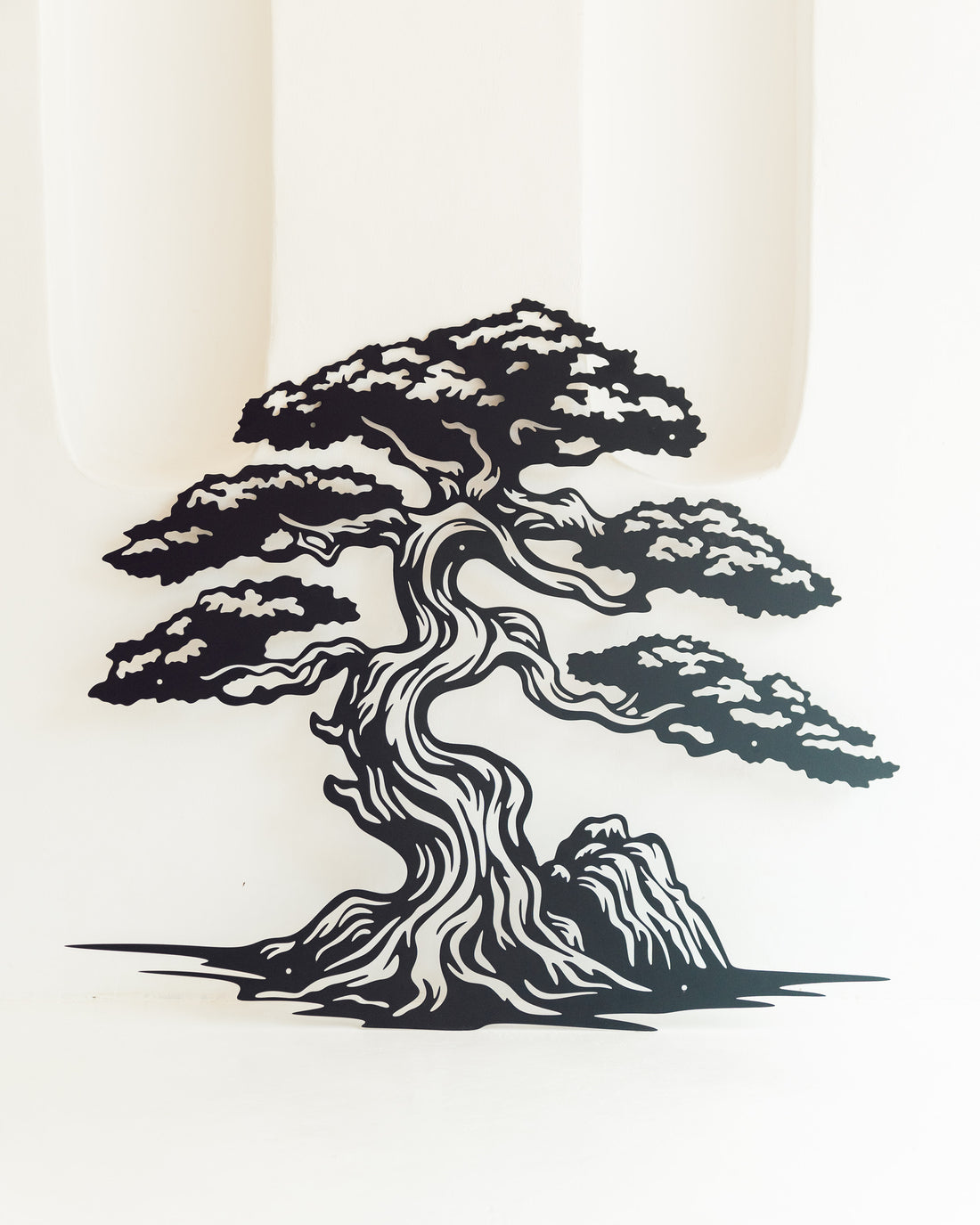 Detailed bonsai tree design in intricate metalwork, displayed on a neutral wall in a minimalist, contemporary home setting.
