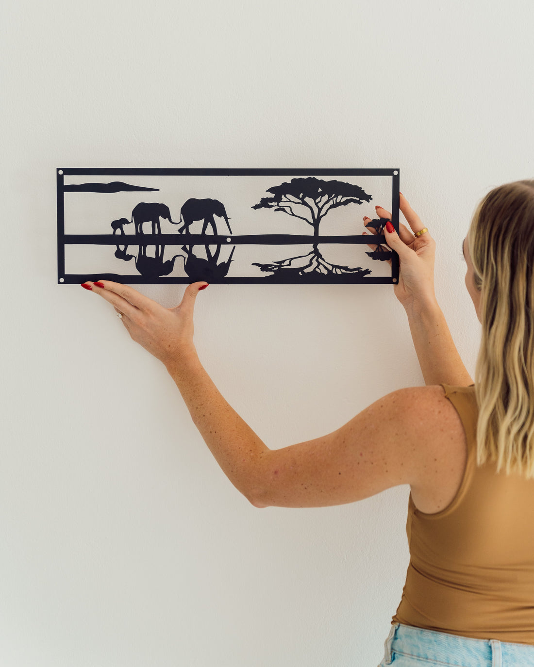 Metal wall art of two elephants walking in a savannah setting, detailed with minimalist lines and naturalistic curves.