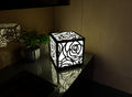 300mm metal cube lamp featuring a blooming rose cut-out pattern, white plexiglass panels, and a textured black finish.